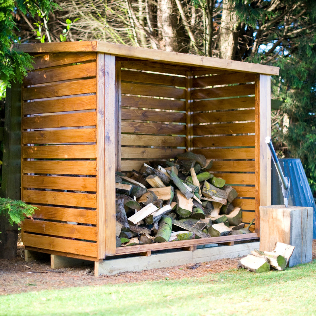 Shire pressure-treated timber log store stacked with seasoned firewood in a British garden