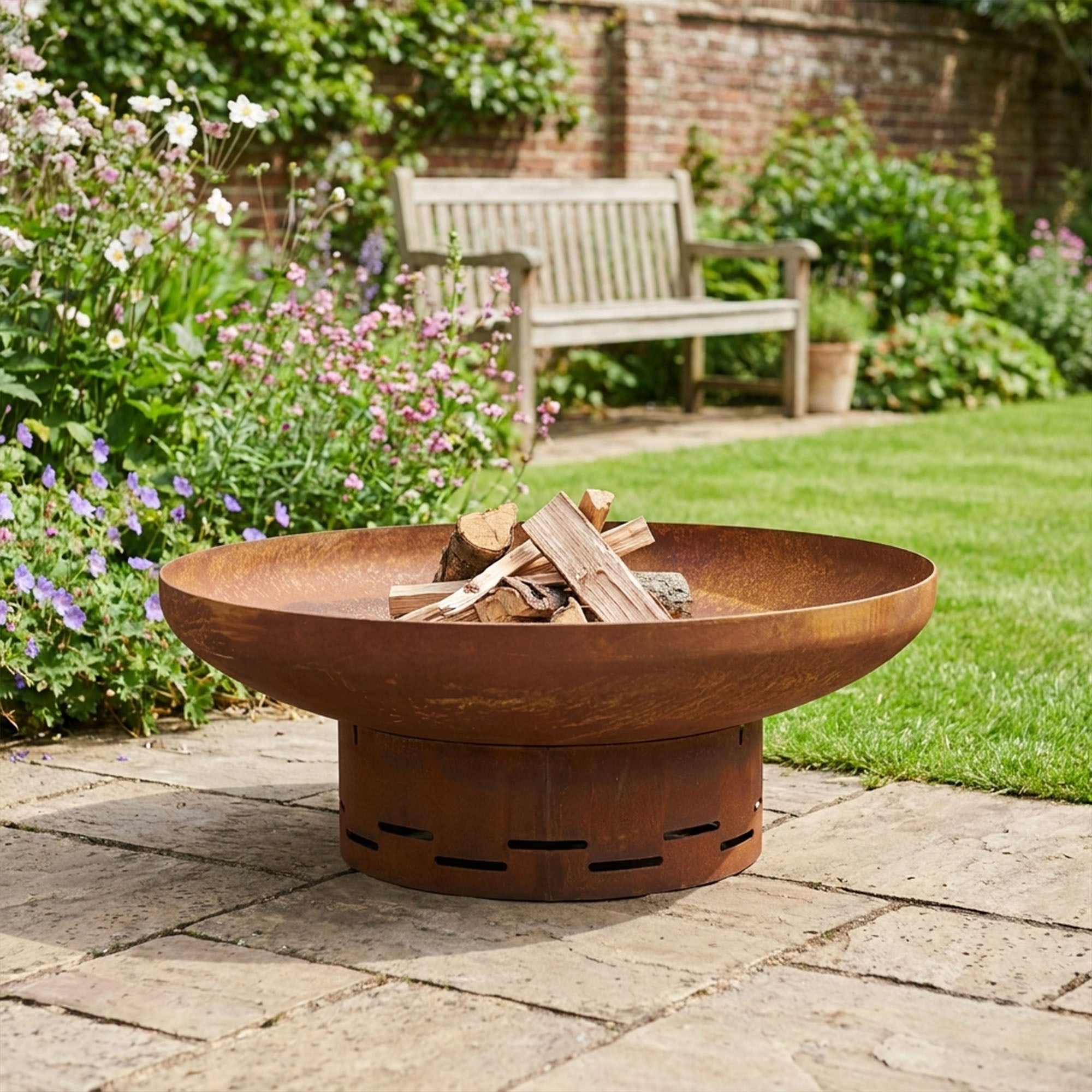 Corten steel round fire pit 70cm with pre-rusted patina, lit in a garden setting
